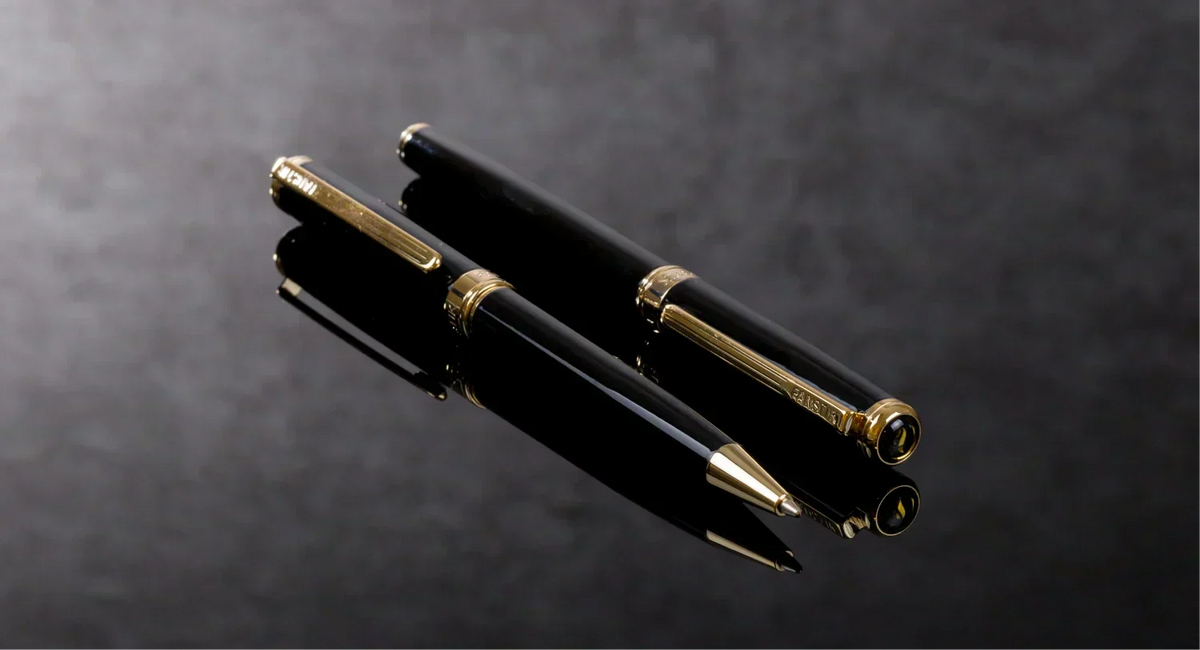 One Fanstik Luxury Rollerball Pen and One Fanstik Luxury Ballpoint Pen on a dark surface